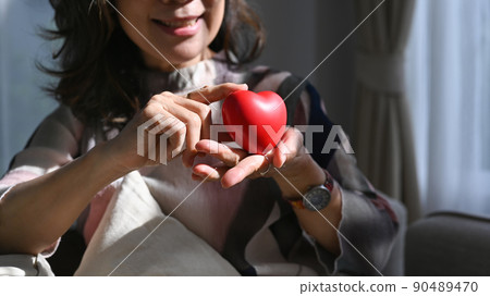 Middle aged woman holding a heart shape in her hands. Elderly care, insurance, heart health and quality of life for elderly concept 90489470