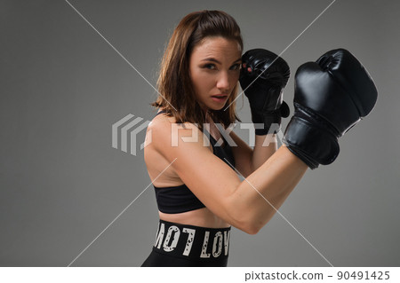 Athletic woman in boxing gloves is practicing karate in studio. 90491425