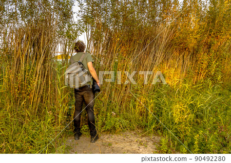 Nature photographer peeking through natural hide 90492280