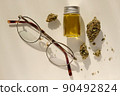 Ophthalmology and cannabis concept. Marijuana buds, ayeglasses and cannabis concentrate oil on beige background. Alternative Glaucoma Therapies 90492824