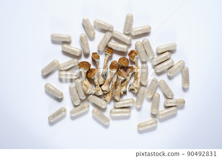 Micro dosing concept. Dry psilocybin mushrooms and herbal pills on grey background Micro dosing concept. Dry psilocybin mushrooms and herbal pills on grey background 90492831