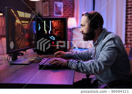 Young adult focusing on online video games championship, playing action game on online live stream. Caucasian player having fun with virtual esport gameplay tournament on computer. Young adult focusing on online video games championship, playing action game on online live stream. Caucasian player having fun with virtual esport gameplay tournament on computer. 90494321