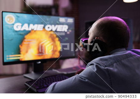 Upset male player losing action video games championship with multiple players on internet. Modern gamer streaming gameplay and feeling frustrated about lost gaming tournament. Upset male player losing action video games championship with multiple players on internet. Modern gamer streaming gameplay and feeling frustrated about lost gaming tournament. 90494333