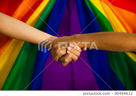 LGBTQ flag and hand. Pride flag symbol of Lesbian Gay Bisexsual Transgender Queer or homosexsual. people holding hand on pride rainbow flag to represent of freedom and equality. 90494612
