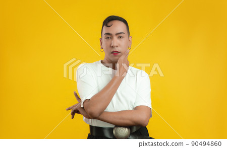 Transgender male posing and looking at camera isolated yellow color background, LGBT pride month concept. Transgender male posing and looking at camera isolated yellow color background, LGBT pride month concept. 90494860
