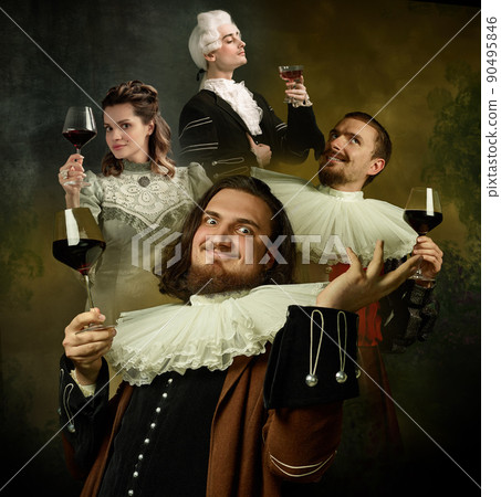 Medieval people as royalty persons in vintage clothing tasting red wine on dark vintage background. Concept of comparison of eras, modernity and renaissance, baroque style. Medieval people as royalty persons in vintage clothing tasting red wine on dark vintage background. Concept of comparison of eras, modernity and renaissance, baroque style. 90495846