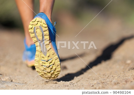 Athlete running sport feet on trail, selective focus on sole.Training workout on off road trail track design in advertising poster style Athlete running sport feet on trail, selective focus on sole.Training workout on off road trail track design in advertising poster style 90498104