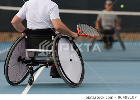 Men on wheelchair playing tennis on tennis court 90498107