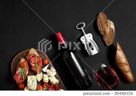Red wine, cheese, cherry tomato, bread and prosciutto on wooden board over black backdrop, top view, copy space Red wine, cheese, cherry tomato, bread and prosciutto on wooden board over black backdrop, top view, copy space 90498359