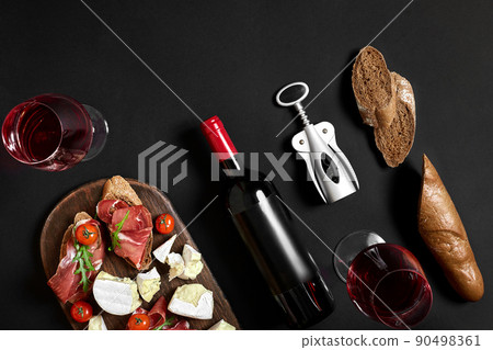 Red wine, cheese, cherry tomato, bread and prosciutto on wooden board over black backdrop, top view, copy space Red wine, cheese, cherry tomato, bread and prosciutto on wooden board over black backdrop, top view, copy space 90498361
