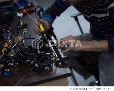Industrial worker man soldering cables of manufacturing equipment in a factory. Selective focus 90498458