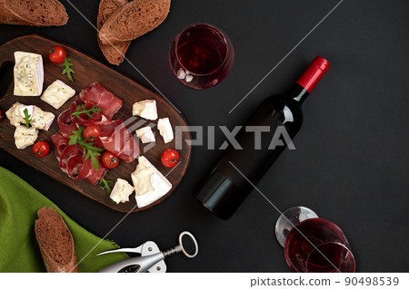 Red wine, cheese, cherry tomato, bread and prosciutto on wooden board over black backdrop, top view, copy space Red wine, cheese, cherry tomato, bread and prosciutto on wooden board over black backdrop, top view, copy space 90498539