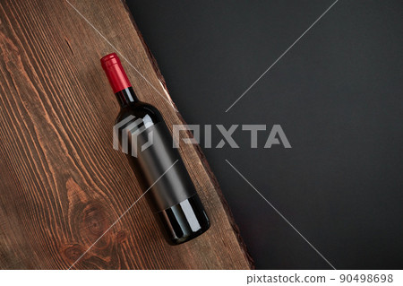 Bottle of wine on the wooden board on black background. Top view with copy space Bottle of wine on the wooden board on black background. Top view with copy space 90498698