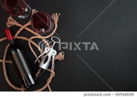Red wine bottle, two glasses and corkscrew on black background. Top view with copy space Red wine bottle, two glasses and corkscrew on black background. Top view with copy space 90498699