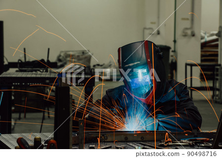 Professional Heavy Industry Welder Working Inside factory, Wears Helmet and Starts Welding. Selective Focus 90498716