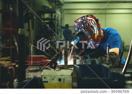 Professional Heavy Industry Welder Working Inside factory, Wears Helmet and Starts Welding. Selective Focus 90498769