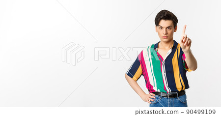 Disappointed young man prohibit something, shaking finger in disapproval, forbid you, standing over white background 90499109