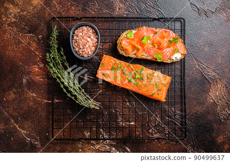 Open sandwich toast with cold smoked salmon fillet, spices. Dark background. Top view 90499637
