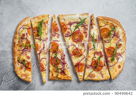 French tarte flambee with cream cheese, bacon, tomato and onions. Flammkuchen from Alsace region. White background. Top view French tarte flambee with cream cheese, bacon, tomato and onions. Flammkuchen from Alsace region. White background. Top view 90499642