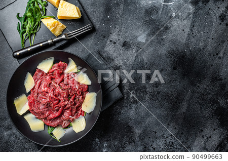 Carpaccio salad with marbled beef meat, arugula and Parmesan. Black background. Top view. Copy space 90499663