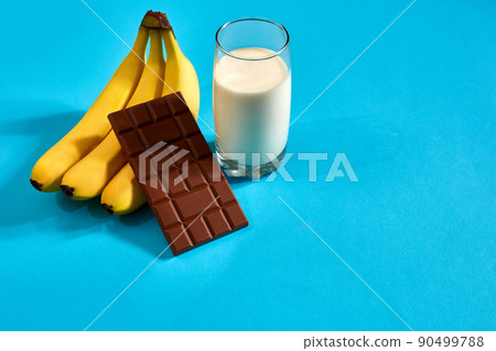 Glass of milk with bananas and chocolate on blue background Glass of milk with bananas and chocolate on blue background 90499788
