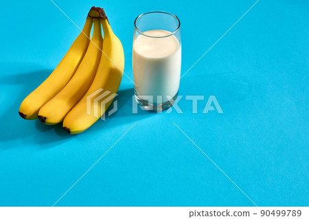 Glass of milk with bananas over blue background Glass of milk with bananas over blue background 90499789