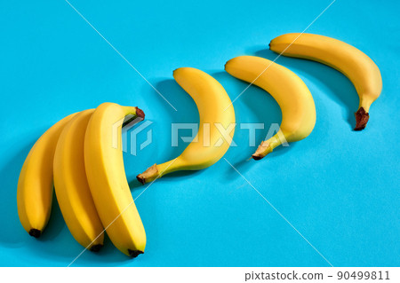 Yellow ripe bananas on blue background with space for text or design. Top view 90499811