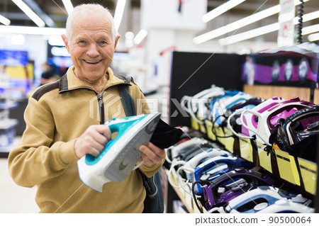 elderly man choosing iron in showroom of electrical appliance store 90500064