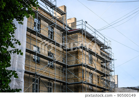Reconstruction of an old brick house. Scaffolding for construction, construction site. Selective focus 90500149