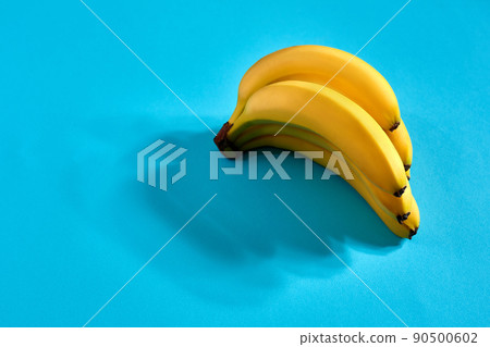 Yellow ripe bananas on blue background with space for text or design. Top view 90500602