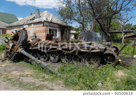 A burnt Russian tank near a residential building. War in Ukraine 2022. Russian missiles in Kharkiv countryside Ukraine. Russian aggression. Russian attack on Ukraine. A burnt Russian tank near a residential building. War in Ukraine 2022. Russian missiles in Kharkiv countryside Ukraine. Russian aggression. Russian attack on Ukraine. 90500638