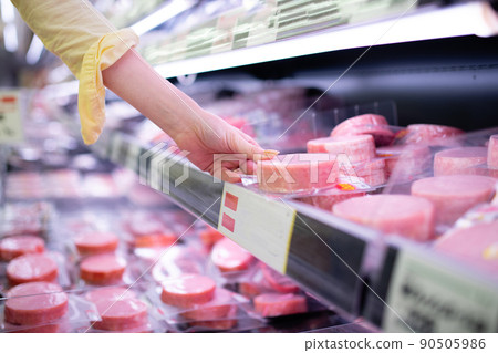 Women's hands picking up ham in a supermarket Women's hands picking up ham in a supermarket 90505986