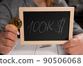 A woman holding a board with the inscription 100 thousand dollars and a bitcoin. 90506068