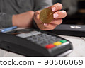 Close-up woman holding golden bitcoin coin near terminal for payment. 90506069