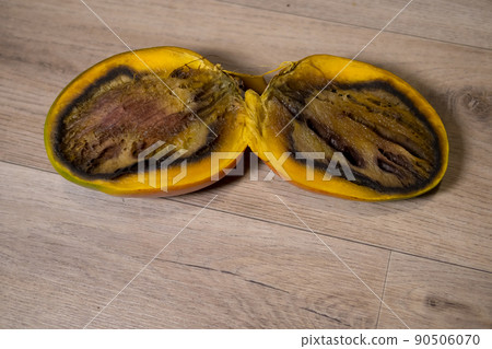 Close-up of a completely rotten cut mango on a wooden background Close-up of a completely rotten cut mango on a wooden background 90506070