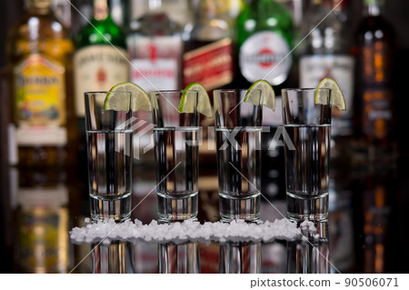 Close-up of a shots of tequila with lime and salt in a bar. 90506071