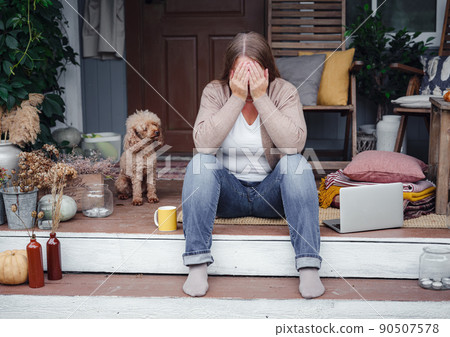 middle aged depressed woman sitting on porch. 90507578