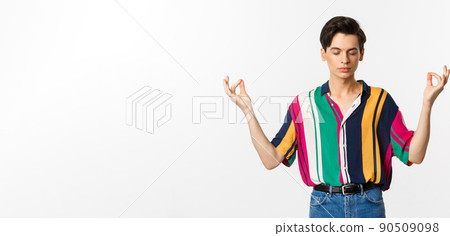 Image of young man meditating, holding hands in zen gesture and close eyes, relaxing and standing over white background 90509098