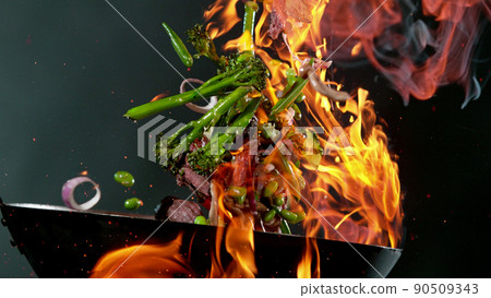 Closeup of chef throwing beef pieces with vegetable. Closeup of chef throwing beef pieces with vegetable. 90509343