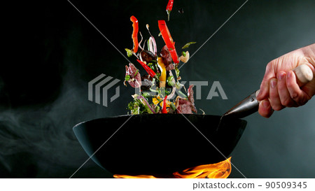 Closeup of chef throwing beef pieces with vegetable. Closeup of chef throwing beef pieces with vegetable. 90509345