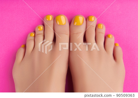 Womans feet with spring summer nail design on pink background. Body treatment 90509363