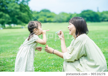 Parents and children playing with soap bubbles 90510278
