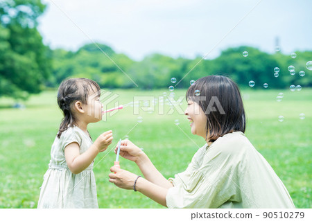 Parents and children playing with soap bubbles 90510279