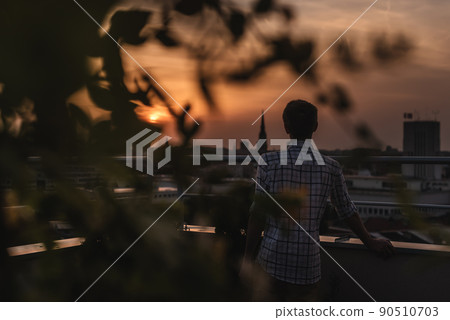 Man Watching Sunset on Rooftop Garden 90510703