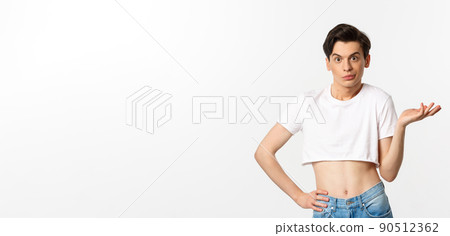 Handsome androgynous man in crop top looking confused, shrugging clueless, standing over white background 90512362