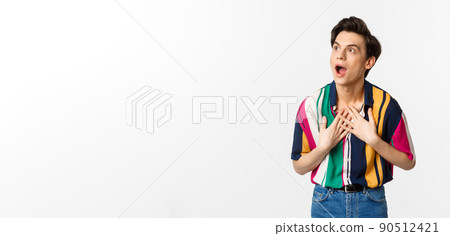 Impressed young handsome man looking at upper left corner, express disbelief and amazement, seeing promo offer, white background 90512421