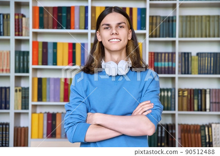 Portrait of a smiling guy student looking at the camera in the library Portrait of a smiling guy student looking at the camera in the library 90512488