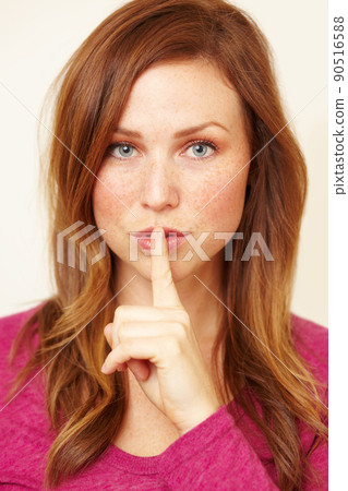 Ssh..you didnt hear it from me. Portrait of a beautiful young woman with her finger to her lips. Ssh..you didnt hear it from me. Portrait of a beautiful young woman with her finger to her lips. 90516588