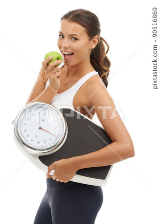 Tasty and healthy. A fit young woman carrying a scale and enjoying a delicious apple. Tasty and healthy. A fit young woman carrying a scale and enjoying a delicious apple. 90516869