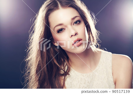 Stunning model in the limelight. A gorgeous young woman backlit with bright lights while isolated on black. 90517139